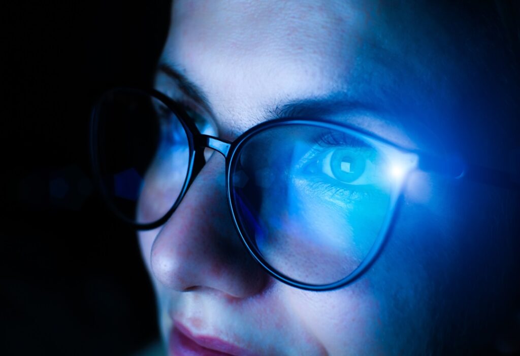 Junge Frau mit Brille vor einem Bildschirm. Hautschutz vor Bluelight